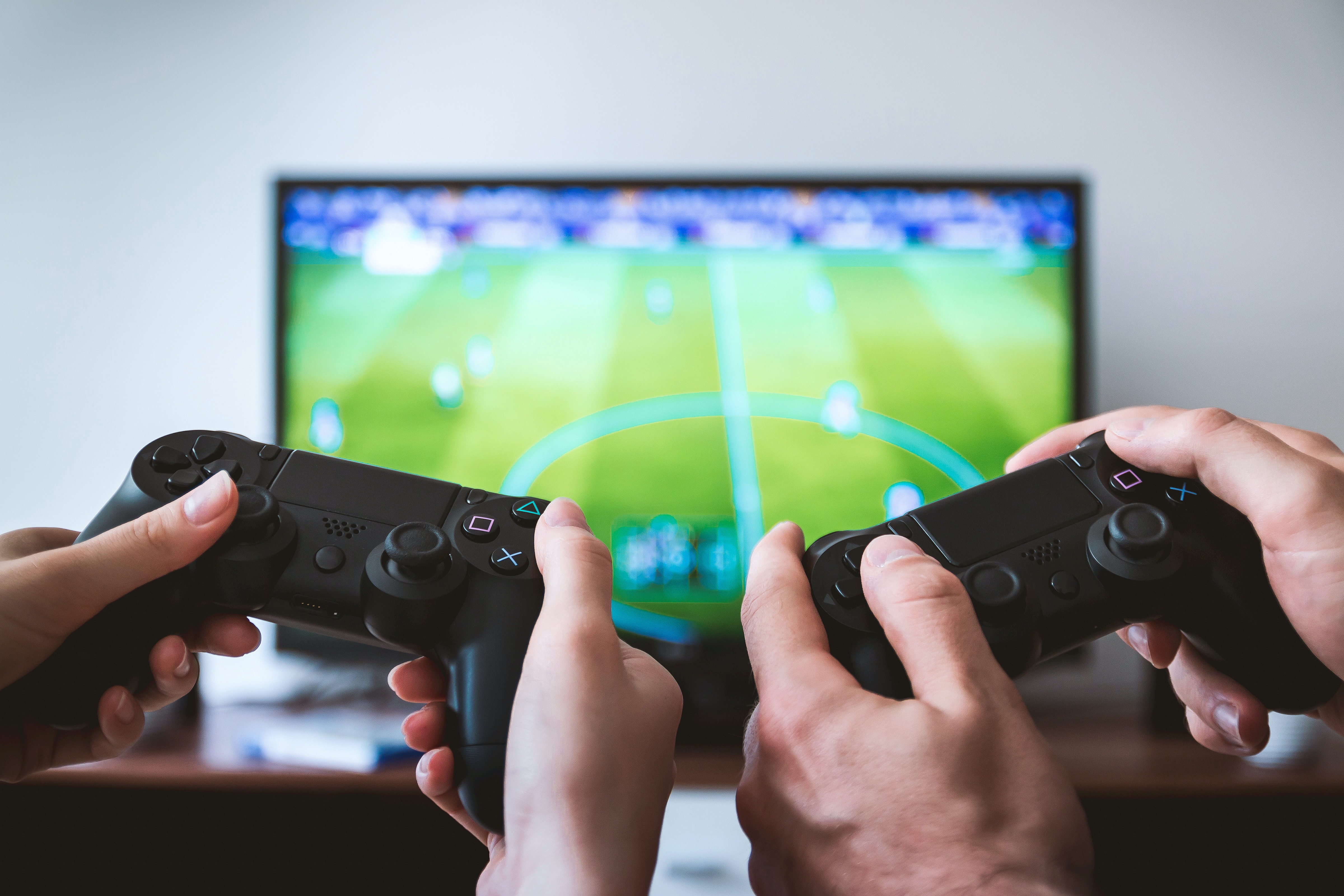  picture of a tv and two people holding ps4 joysticks